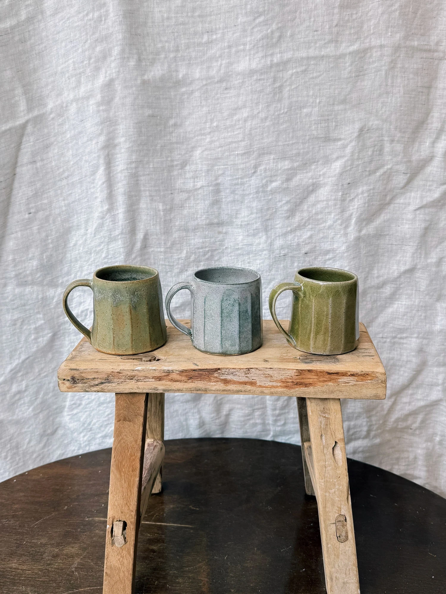 Three mugs on a wooden stall.